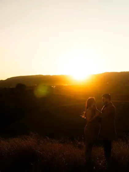 A wide silhouette of the couple against the sunset, capturing the epic scale of the landscape and the intimacy of their embrace.