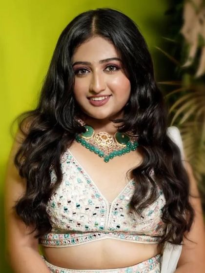A close-up of the model in the white floral lehenga, highlighting the statement green beaded necklace.