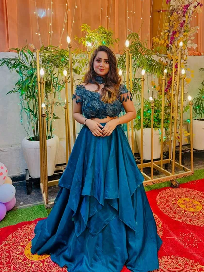 A full view of the dramatic teal lehenga. The tiered skirt and unique blouse design make it a perfect choice for a portfolio shoot or a cocktail party.