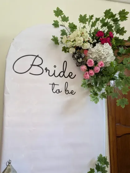 A simple yet elegant 'Bride to be' backdrop. The white arched panel is decorated with a beautiful floral and greenery arrangement for a fresh, clean look.