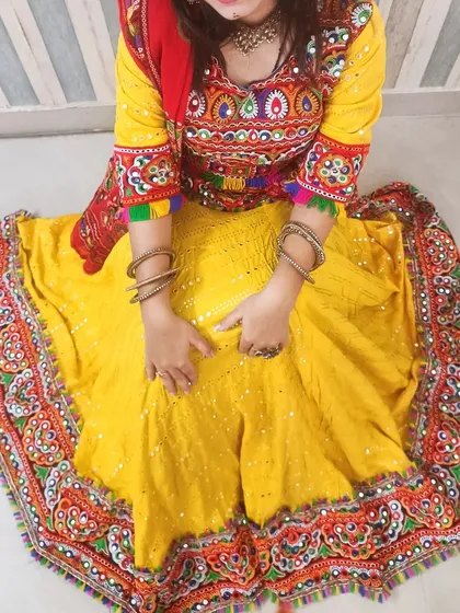 An overhead view of the popular yellow Navratri chaniya choli, showcasing the full flare of the skirt and the intricate, multi-colored embroidery on the blouse and border.