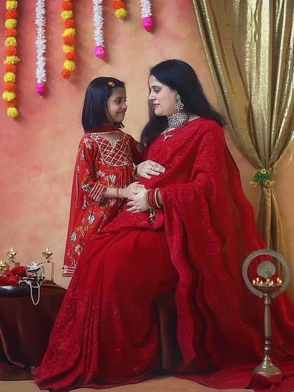 The special bond between a mother and her daughter as they wait for the new baby. The flowing red saree and traditional decor make this maternity photo feel so timeless and elegant.