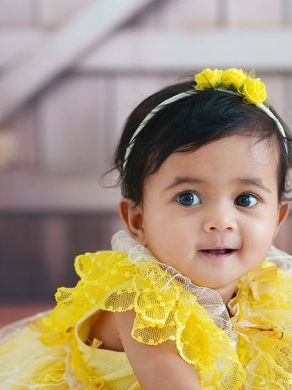 A classic and beautiful close-up of a baby girl. Her bright eyes and sweet smile are perfectly captured in this simple and timeless portrait.