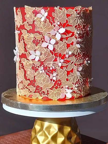 Cake decorating is an art form. This regal red cake, adorned with intricate edible gold lace and delicate wafer paper flowers, showcases the advanced techniques you can master in my specialized workshops.