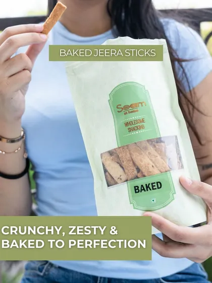 A woman enjoying my Baked Jeera Sticks. They are crunchy, zesty, and baked to perfection, offering a light yet flavourful snack for any time of day.