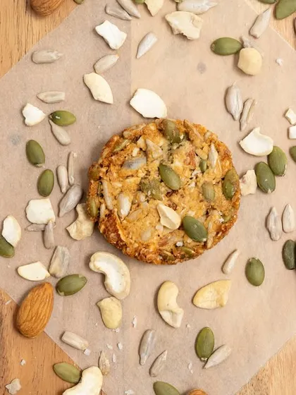 A single multi-seed cookie, showing the care and quality of ingredients in each one. It's a perfect, wholesome bite.