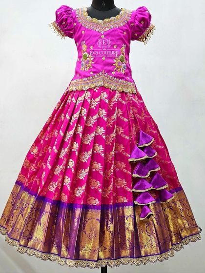A grand pink and purple Banarasi lehenga with a scalloped lace border and a side cascade of tassels.