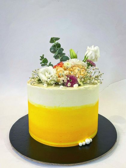 This cake just screams summer with its bright yellow ombre buttercream and a fresh, rustic arrangement of flowers on top. It's a simple yet stunning design for any happy occasion.