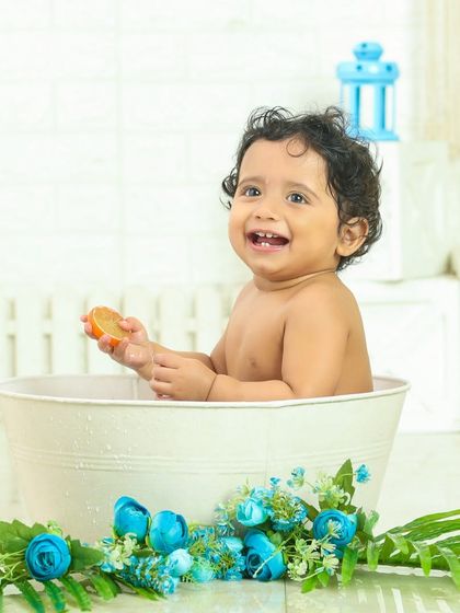 A huge, happy smile from the tub. This little one is having the time of her life during this fun and splashy bath time photoshoot.