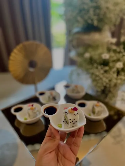 A hand holding a delicate plate of sushi, showcasing the elegant and personal service we provide at anniversary parties.