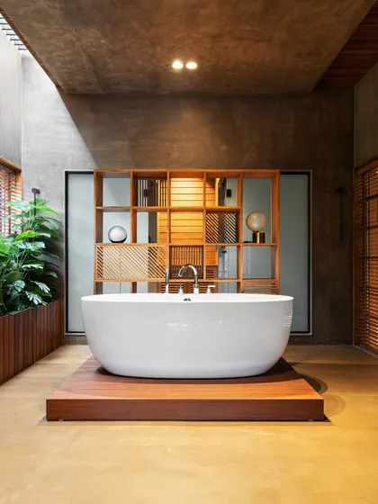 We designed this spa-like bathroom in the Faizal Residence to be a private sanctuary. The freestanding tub is the centerpiece, elevated on a wooden platform and surrounded by natural materials, with a skylight that bathes the room in soft, natural light.