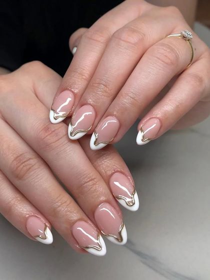 A modern, artistic take on the French manicure. These almond nails have a classic white tip with a creative, dripping gold metallic overlay.