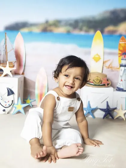 Capturing the biggest smiles during a beach-themed sitter session. The combination of a joyful expression and fun props like surfboards and an anchor creates a perfect holiday vibe.