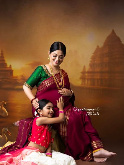 A mother and daughter share a quiet moment during a traditional maternity shoot, set against a beautifully painted backdrop.