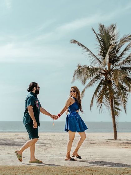 A romantic walk on a Goan beach. This classic pre wedding shot captures the couple against a backdrop of palm trees and the ocean, creating a timeless and beautiful image.