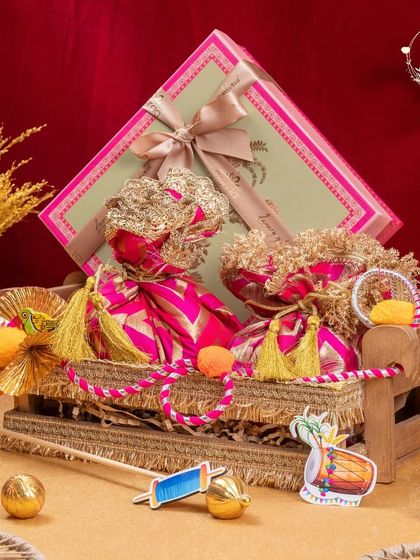 A beautiful Lohri hamper featuring a miniature manji (bedstead) decorated with colourful potlis and a box of sweets. It's a truly unique and traditional gift.