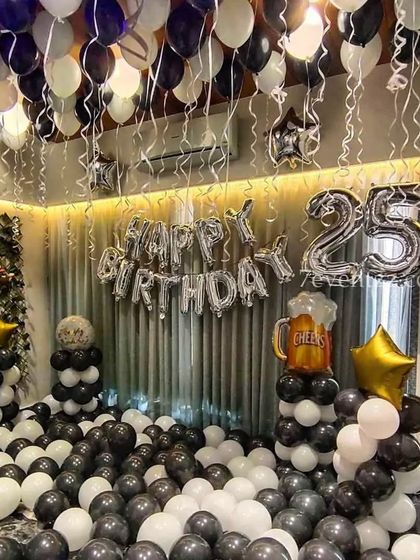 A 25th birthday room decoration in black and white, with balloon pillars and a beer mug foil balloon.