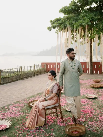 A portrait that feels like a classic painting, rooted in tradition. The couple's pose against the serene waterside setting reflects the quiet beauty and heritage of their South Indian wedding.