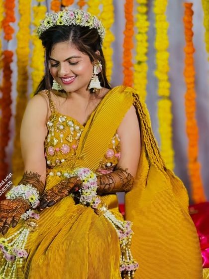 A radiant bride during her haldi or mehndi ceremony, wearing floral jewelry that perfectly complements her intricate henna designs.