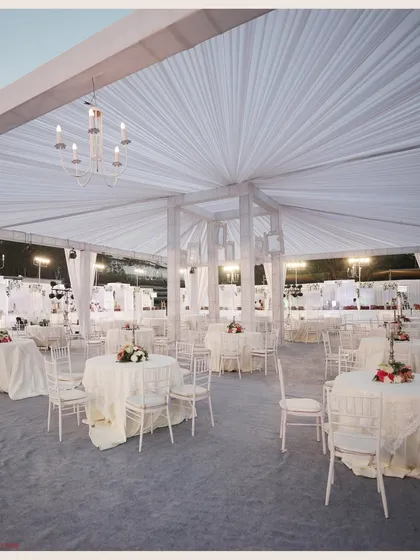 The dining area of the "White Wonder" event. The space is defined by white drapes, elegant chandeliers, and classic Chiavari chairs, creating a cohesive and sophisticated atmosphere for guests.