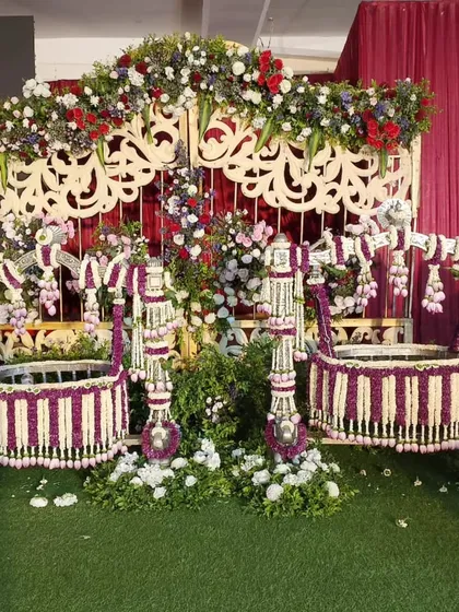A unique cradle decoration featuring two cradles for a twin naming ceremony, both adorned with purple and white flowers.