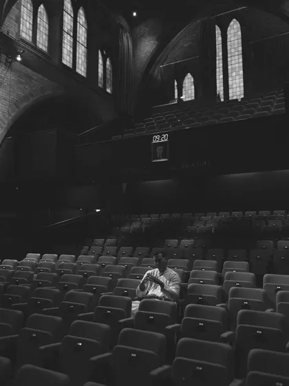 Sitting alone in the empty seats of a theater before a show. It's a moment of quiet reflection, visualizing the performance and connecting with the history of the venue.