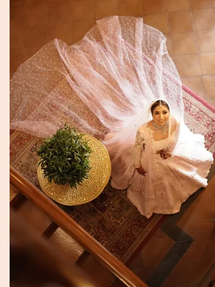 An aerial shot of the bride looking up, with her long veil spread out around her. This creative angle provides a unique and beautiful bridal portrait.
