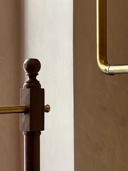 A close-up of the custom brass and wood joinery for the clothing display racks at Eka. This detail shows the intersection of modern brass fittings with traditional woodcraft, a key theme in the store's design.