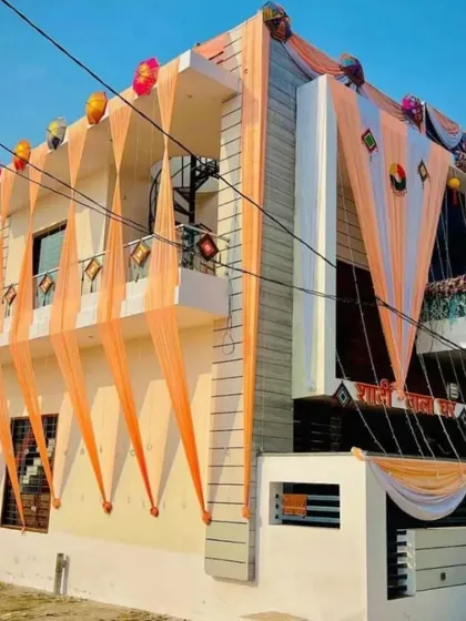 A full view of a house exterior decorated for a wedding celebration. The facade is adorned with flowing peach and white drapes, creating a grand and welcoming entrance for guests. This type of home wedding decoration sets a festive tone for the entire neighborhood.