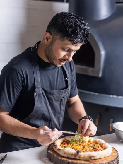 Adding the final touches to a freshly baked pizza right out of the wood-fired oven. It's these small details and the passion behind them that define the food at Camillo's.