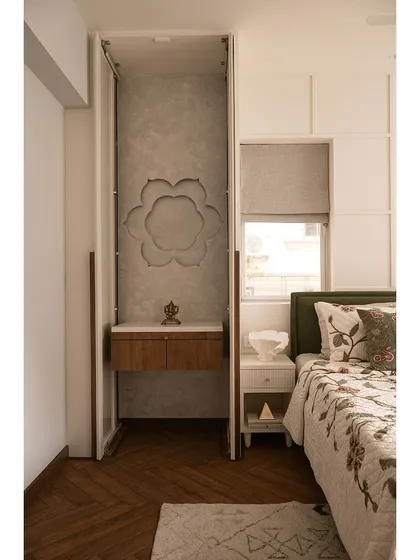 The mandir in this guest bedroom is concealed behind elegant pocket doors. When opened, it reveals a serene prayer space with a textured back panel and a small wooden altar, blending spirituality with modern design.
