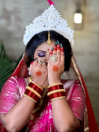 A creative pose showing the alta on the hands and the beautiful eye makeup of a Bengali bride.