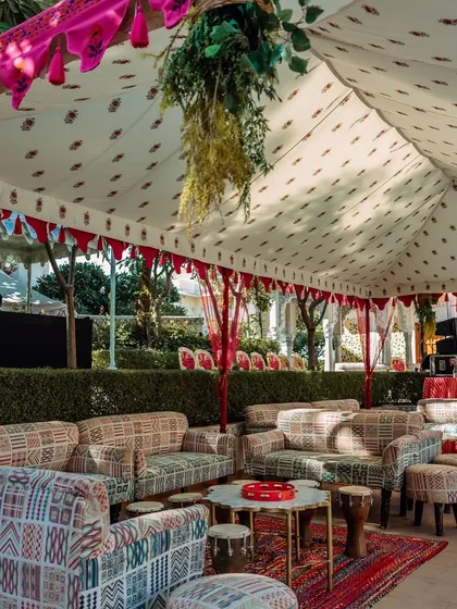 A chic and comfortable lounge area for a Haldi ceremony at The Leela Palace Jaipur. The setup features block-printed sofas and traditional Rajasthani textiles under a tent, blending modern comfort with royal charm.