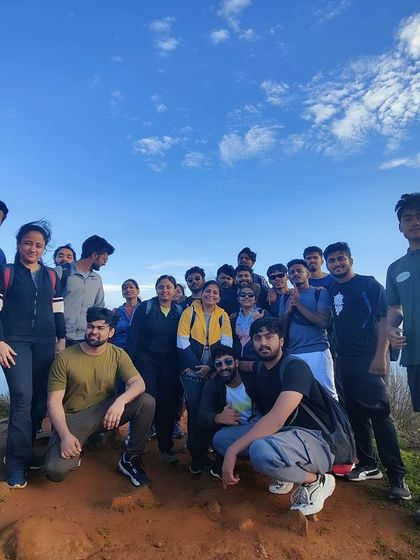 A group photo under the clear blue sky at the Skandagiri summit.