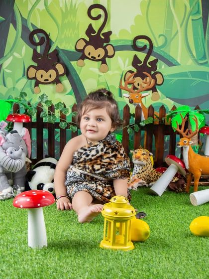A full view of the jungle theme, with a baby sitting among plush elephants, pandas, and deer.