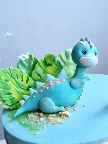 A close-up of the blue brontosaurus topper, showing the texture and details on its back.