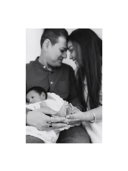 A classic black and white family portrait, holding their newborn's tiny feet. This style creates a timeless and emotional memory of your family's beginning.