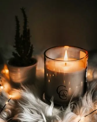 This is my classic C&C branded jar candle, creating a warm and inviting glow. Placed on a soft surface with fairy lights, it shows how a simple scented candle can transform your space into a cozy sanctuary.