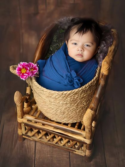 Even when they are awake, we can capture beautiful moments. This alert newborn looks right at the camera from a cozy basket, showing off their curious eyes.