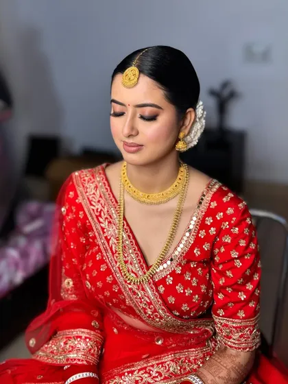 Elegance meets radiance in this bridal glam for Salena. Her simple gold jewelry and classic red lehenga are paired with a soft, glowing makeup look and a traditional gajra bun.