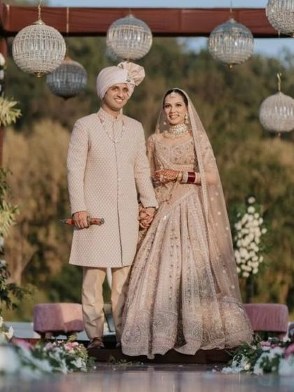 A picture-perfect couple at their destination wedding in the hills. The bride's pastel lehenga and soft makeup look stunning against the natural scenery.