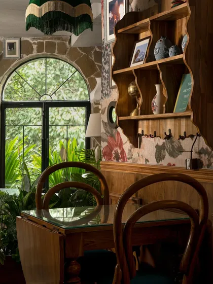 Another view of the intimate seating at Echoes. The mix of bentwood chairs, a glass-topped table, and floral wallpaper against a stone arch creates a layered, maximalist aesthetic that feels both personal and curated.