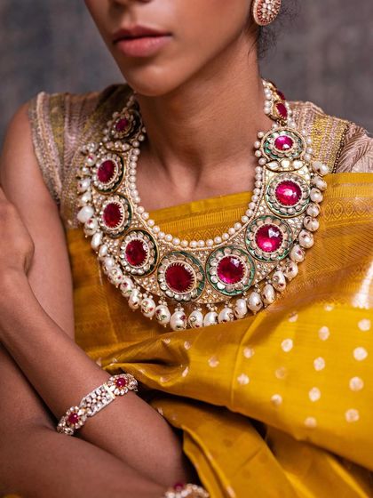 A detailed shot of the ruby and pearl bridal necklace, a magnificent piece of jewelry that elevates the yellow silk saree.
