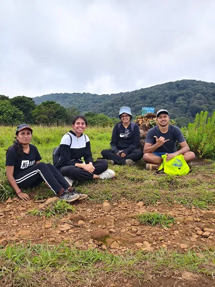 A group of friends taking a break on the grassy trail of the Kudremukha trek.
