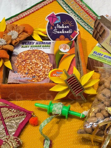 A simple yet beautiful Makar Sankranti hamper, featuring traditional sweets and a decorative kite and spool.