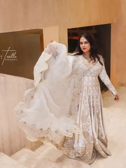 The bride gives her dupatta a playful twirl, showing the beautiful flow and embroidery of her outfit. This action shot adds life and movement to the portrait.