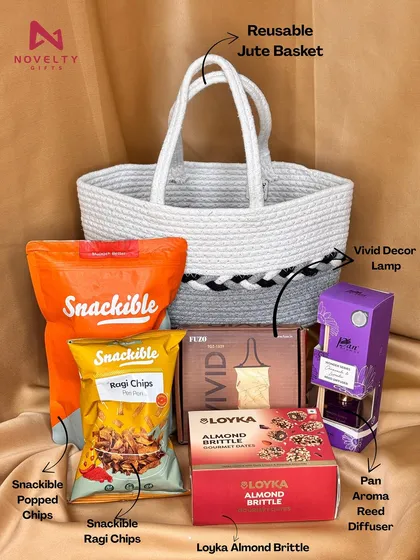 Gifting can be both beautiful and sustainable. This hamper features a reusable jute basket filled with healthy snacks like popped chips and almond brittle, paired with a stylish Vivid decor lamp and a pan aroma reed diffuser. It’s a thoughtful, eco-friendly gift option.