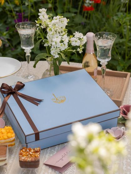A close-up of our elegant blue gift box, tied with a brown ribbon. It’s designed to hold a dozen of our handcrafted dessert cups, making it a substantial and impressive gift for any celebration.