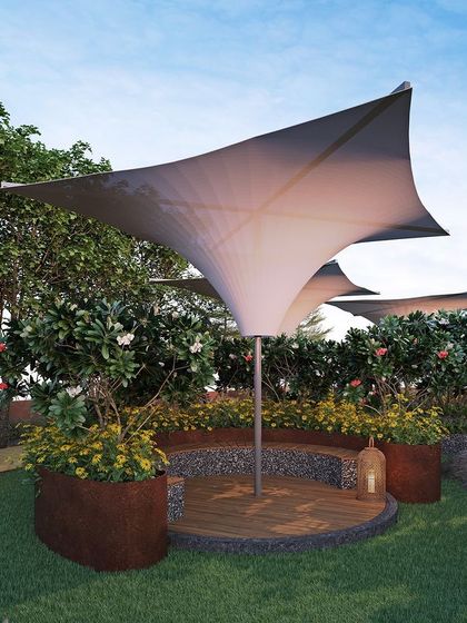 Sculptural tensile canopies provide shade and visual interest in this garden seating nook. The curved forms contrast with the organic shapes of the surrounding flowers and trees, creating a dynamic composition.