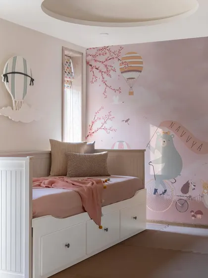Another view of the children's room, highlighting the soft pink hues and whimsical wallpaper. The space includes a daybed with built-in storage, making it both magical and practical.